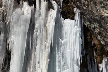 Icy mountain waterfall at winter sun dayの写真素材
