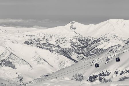 Snowy mountains and gondola lift at sunny winter day. Caucasus Mountains, Shahdagh, Azerbaijan. Black and white retro toned landscape.の写真素材
