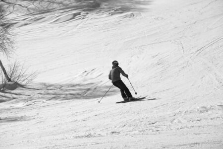 Skier downhill on snowy ski slope at sunny day. Caucasus Mountains in winter. Hatsvali, Svaneti region of Georgia. Black and white toned image.の写真素材