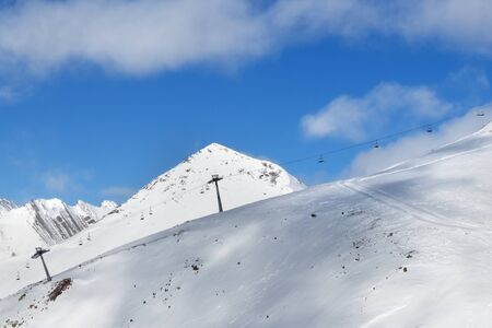 Off-piste snowy slope and chair-lift on ski at sunny day. Caucasus Mountains in winter, Georgia, region Gudauri, Mount Sadzele.の写真素材