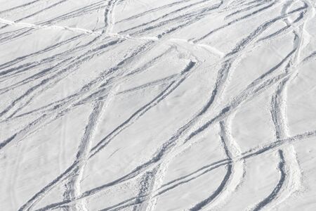 Snowy off-piste ski slope with trace from skis and snowboards at sunny winter dayの写真素材