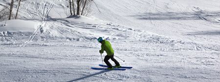 Skier downhill on snowy ski slope at sunny winter day. Caucasus Mountains. Hatsvali, Svaneti region of Georgia. Panoramic view.の写真素材