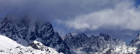 Snowy rocks in clouds at sunny winter day. Caucasus Mountains. Georgia, region Svaneti. Panoramic view.の写真素材