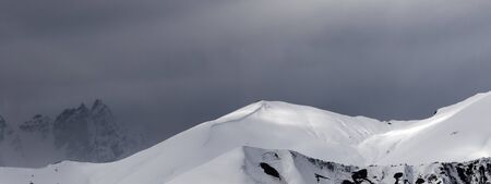 Panoramic view on sunlight mountains with snow cornice and trace from avalanche before blizzard. Caucasus Mountains. Svaneti region of Georgia at winter.の写真素材