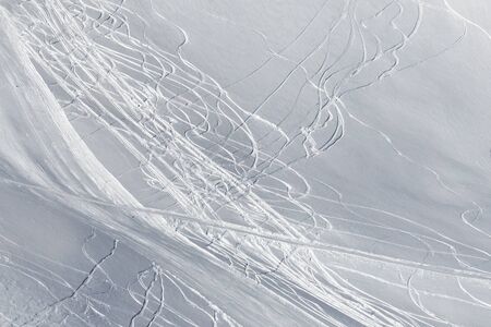 View on snowy off-piste slope with traces of skis and snowboards in sun winter dayの写真素材