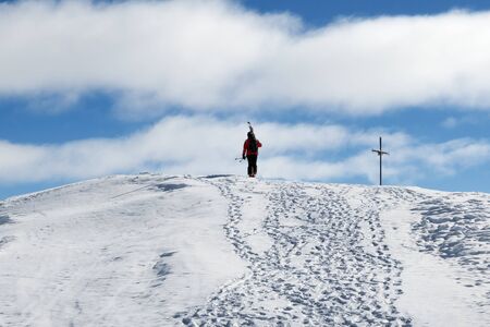 Skier with skis on his shoulder go up to top of snowy mountain in nice sun day. Caucasus Mountains in winter, Georgia, region Gudauri, Mount Kudebi.の写真素材