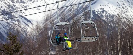 Father and daughter on chair-lift at nice sunny day. Caucasus Mountains. Hatsvali, Svaneti region of...
