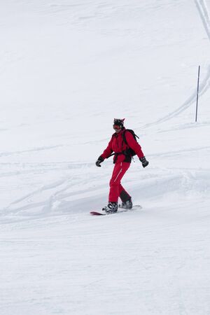 Snowboarder on snowy ski slope after snowfall at winter dayの写真素材