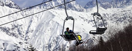 Skiers on ski-lift and snowy mountains at winter sun day. Caucasus Mountains. Hatsvali, Svaneti region of Georgia. Panoramic view.の写真素材
