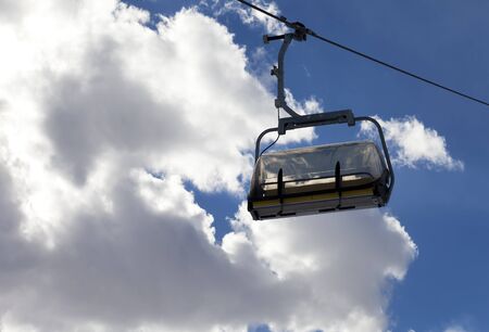 Chair-lift and sunlit sky with clouds at evening. Close-up view.の写真素材