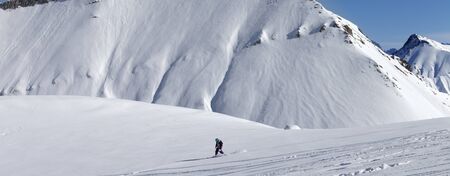 Snowboarder downhill on snowy off piste slope with newly-fallen snow. Caucasus Mountains, Georgia, region Gudauri at winter. Panoramic view.の写真素材