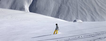 Snowboarder downhill on snowy off piste slope with newly-fallen snow. Panoramic view.の写真素材