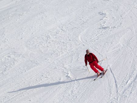 Skier on snowy sunlit ski slope at sun winter dayの写真素材