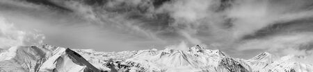 Larger panorama of winter snowy mountains and sky with sunlit clouds. Caucasus Mountains,...