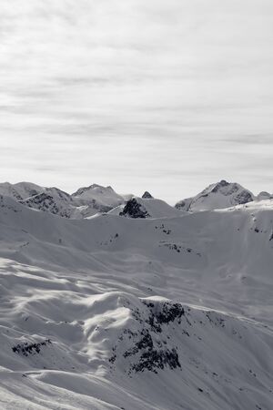 Snowy off-piste ski slope at high winter mountains and sunlit cloudy sky at evening. Italian Alps. Livigno, region of Lombardy, Italy. Black and white toned landscape.

の写真素材