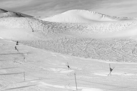 Trace for ski slalom with gates marked by flags, prepared by snowcat and off-piste slope in snowy...