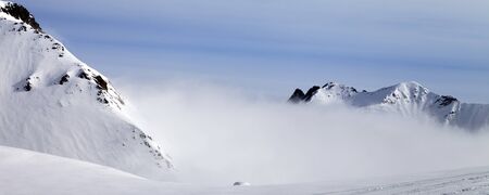 Panoramic view on off-piste ski slope and snowy high mountains in mist. Caucasus Mountains. Georgia, region Gudauri at winter.の写真素材