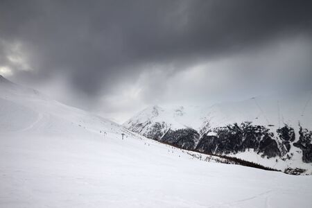 Snowy ski slope in high mountains and cloudy storm sky at winter before blizzard. Ski area Mottolino Fun Mountain, Italian Alps at bad weather. Livigno, Lombardy, Italy, Europe.の写真素材