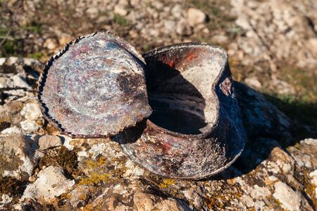 Old rusty tin can covered with ash on stone at sunny day. Concept of environmental pollution,...