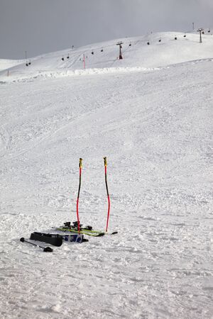 Skiing equipment: ski poles, skis on snowy slope, chair lift and gray cloudy sky at background. Ski area Mottolino Fun Mountain, Italian Alps in winter evening. Livigno, Lombardy, Italy, Europe.の写真素材