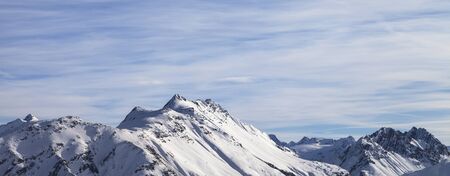 Snowy high winter mountains and beautiful cloudy sunlit sky. Italian Alps. Livigno, region of Lombardy, Italy, Europe. Panoramic view.の写真素材