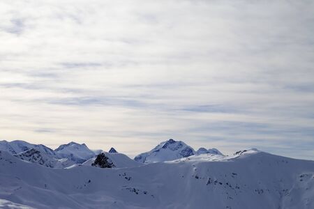 High winter mountains with snowy slopes and sunlit cloudy sky at evening. Italian Alps. Livigno, region of Lombardy, Italy, Europe.の写真素材