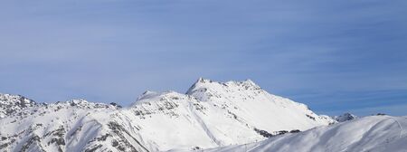 Snowy slope with cableway in high winter mountains and blue sunlit cloudy sky. Italian Alps. Livigno, region of Lombardy, Italy, Europe. Panoramic view.の写真素材