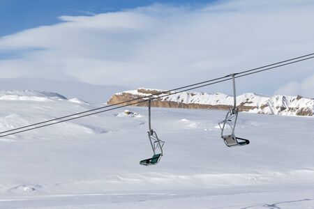 Snowy slope, chair-lift and blue sky with clouds at sun winter evening. Caucasus Mountains, Shahdagh, Azerbaijan.の写真素材