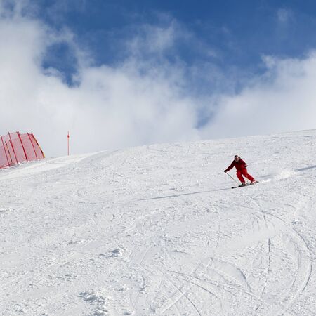 Skier downhill on snowy ski slope at sun winter dayの写真素材