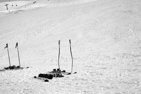 Skiing equipment: ski poles, skis on snowy sunlit slope at winter day. Black and white toned image.の写真素材