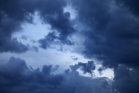 Blue sky with dark storm clouds at sunset. Natural background.の写真素材