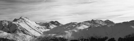Panorama of snowy slope in high winter mountains and sunlit cloudy sky at evening. Italian Alps. Livigno, region of Lombardy, Italy, Europe. Black and white toned landscape.

の写真素材