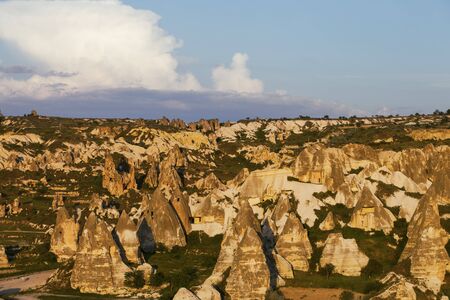 View on evening sunlit Cappadocia valley with cave houses in rocks in spring. Turkey, Goreme.の写真素材