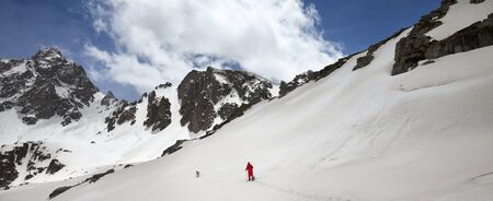 Hiker in snowshoes with dog in high snowy mountain and blue sky with clouds. Turkey, Kachkar Mountains, highest part of Pontic Mountains. Panoramic view.の写真素材