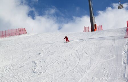 Skier downhill on snowy ski slope at sun winter dayの写真素材