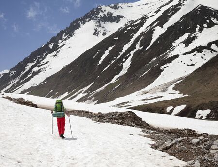 Hiker with big hiking backpack walking on snow covered glacier in high mountains at sunny spring day. Turkey, Kachkar Mountains (highest part of Pontic Mountains).の写真素材