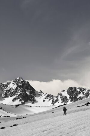 Hiker on snowy plateau, snow covered mountain range and sunlit sky with clouds at sun day. Turkey, Kachkar Mountains, highest part of Pontic Mountains. Black and white retro toned landscape.の写真素材