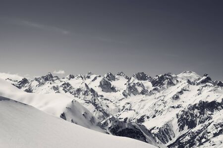 Snow covered mountains, snowy off-piste slope for freeriding and mount Elbrus at background. View from region Dombay, Caucasus Mountains in winter. Black and white retro toned landscape.の写真素材