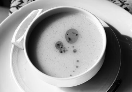 Turkish traditional lentil mashed soup (Turk Mercimek Ãorbasi) on white ceramic bowl and slice of lemon on plate. Black and white toned image. High contrast. 
の写真素材