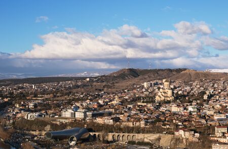Tbilisi city view, capital of Georgia at sunny day. View on Rike park, modern Concert Hall, Presidential Administration, Holy Trinity Cathedral â Sameba and Mtatsminda Mount in clouds with TV tower の写真素材