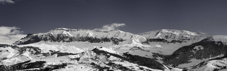 Panorama of high snowy mountains and sky with clouds at sun winter day. Caucasus Mountains, Shahdagh, Azerbaijan. Black and white toned landscape.

の写真素材