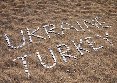 Words Ukraine, Turkey and smile composed of pebble stones on sand beach at summerの写真素材
