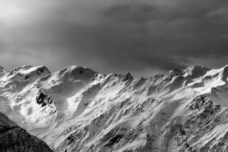 High snowy mountains and sunlight storm sky in winter evening. Caucasus Mountains. Svaneti region of Georgia. Black and white toned landscape.の写真素材