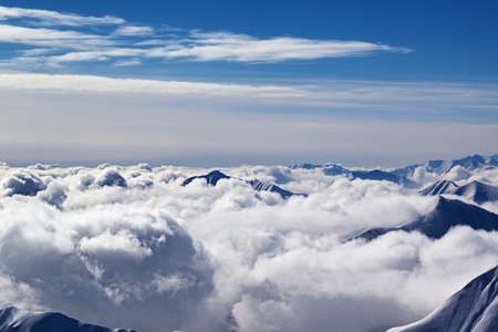 Snowy mountains covered with beautiful sunlight clouds at sunny winter evening. Caucasus Mountains, Georgia, region Gudauri. Plane view.の写真素材