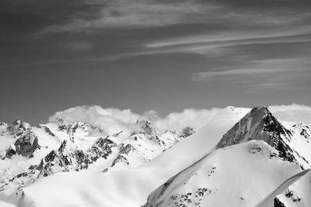 Winter mountains with snow cornice and sky with clouds in nice cold day. Caucasus Mountains, region Dombay. View from the top of mount Musa Achitara. Black and white toned landscape.の写真素材