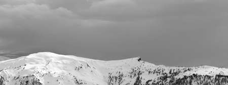 Panoramic view on sunlight snowy mountains and cloudy gray sky in winter evening. Caucasus Mountains, Svaneti region of Georgia. Black and white toned landscape.の写真素材