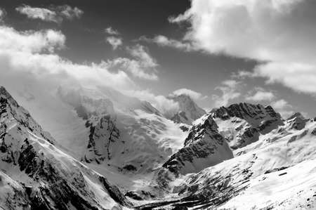 Black and white view on high winter snowy mountains in clouds and fog. Caucasus Mountains, region Dombay. Mount Sulahat.の写真素材