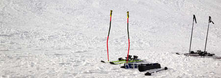 Skiing equipment: ski poles, skis on snowy sunlit slope at winter day. Panoramic view.の写真素材
