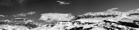 Large panorama of high snowy mountains and sky with clouds at sun winter day. Caucasus Mountains, Shahdagh, Azerbaijan. Black and white toned landscape.の写真素材
