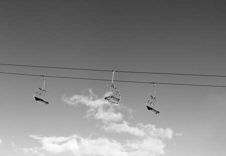 Sunlit ski-lift and sky with clouds at ski resort on sun winter day. Black and white toned image.の写真素材